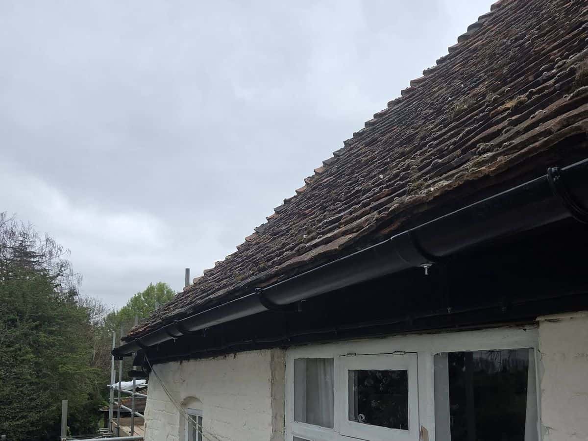 Clay peg tile roof and guttering on a white cottage